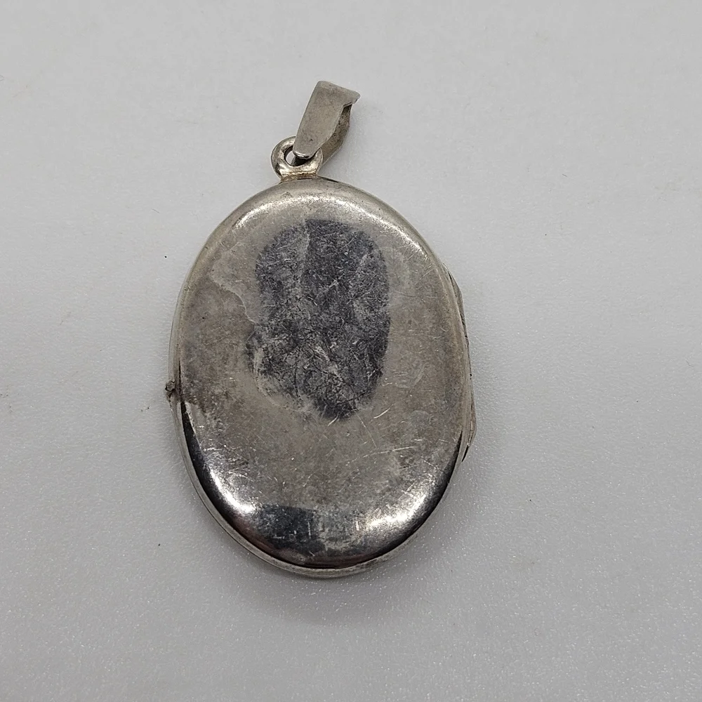 silver tone oval shaped locket style pendant with woman's silhouette